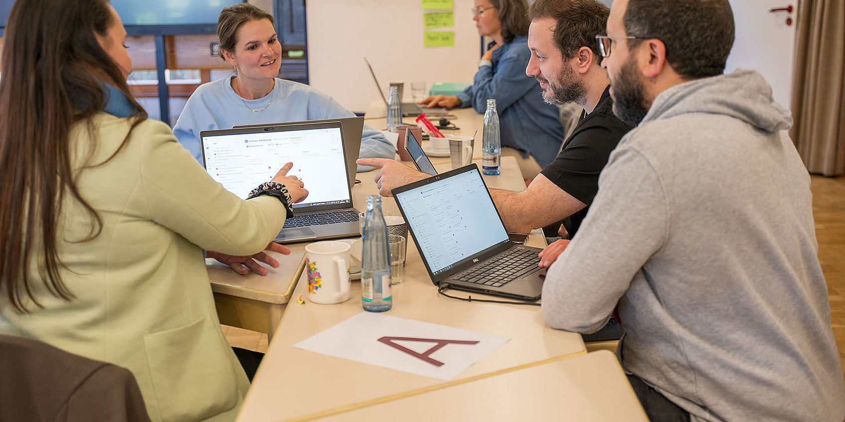 Teilnehmende in Coachingworkshop besprechen Inhalte an Laptops